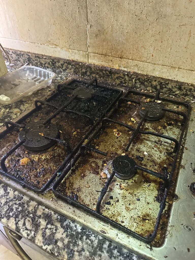Placa de gas con grasa quemada en rejillas y quemadores