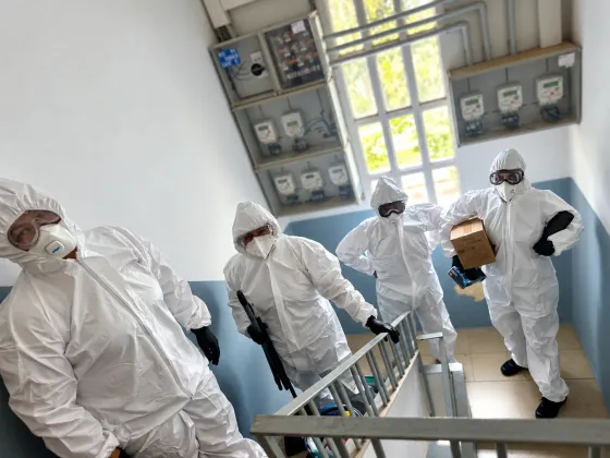 Equipo de Clean Mommy con monos, gafas y mascarillas FFP en la escalera de un edificio