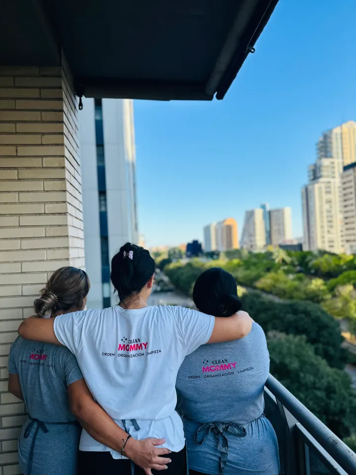 Tres limpiadoras de Clean Mommy de espaldas, con la camiseta del equipo, en una terraza de Benicàssim